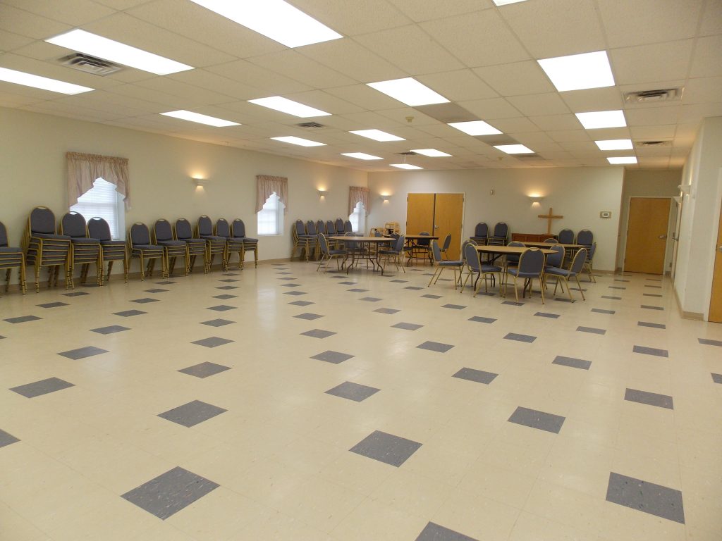 Fellowship hall with several tables surrounded by chairs